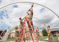 Members of the 201st RED HORSE Squadron set up a shelter to house communications equipment for the 271st Combat Communications Squadron to support the tactical operations center (TOC) functions for Exercise Iron Keystone 2024 at Fort Drum, N.Y., June 7, 2024. Iron Keystone 2024 is a tri-wing exercise including elements of the Pennsylvania Air National Guard's 111th Attack Wing, 193rd Special Operations Wing and the 171st Air Refueling Wing strengthening interoperability between various wing elements in a forward deployed expeditionary environment. (U.S Air National Guard photo by Staff Sgt. Bela Vaszlavik)