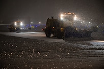 Airmen operate snowplows on the flight line.