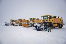 Snow brooms dump snow on the runway.