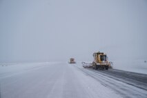 Snow brooms brush the runway free of snow.