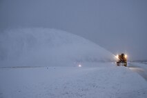 A snowblower clears the runway of snow.