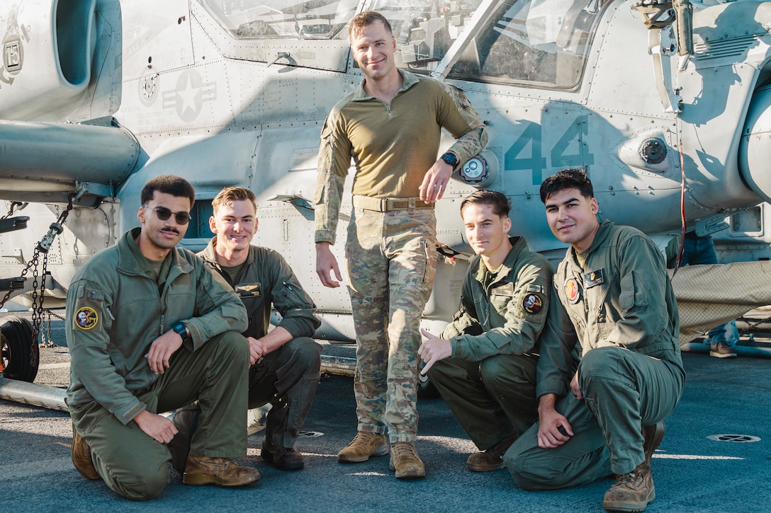 Australian Army Maj. Rhys Davies, center, an AH-1Z Viper pilot assigned to Marine Medium Tiltrotor Squadron (VMM) 165 (Reinforced), 15th Marine Expeditionary Unit, poses for a photo with VMM-165 (Rein.) Marines aboard the amphibious assault ship USS Boxer (LHD 4) while underway in the Pacific Ocean Nov. 21, 2024. Davies recently deployed as part of the 15th MEU’s aviation combat element through the Marine Corps Personnel Exchange Program. In the Australian Army, Davies flew the Tiger Armed Reconnaissance helicopter with 16th Aviation Brigade, 1st Aviation Regiment, and learned to pilot the AH-1Z Viper aircraft upon attaching to VMM-165 (Rein.). (U.S. Marine Corps photo by Cpl. Luis Agostini)