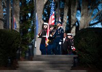 A color guard team of service members from various branches of the military march in a procession.
