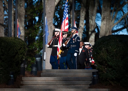 A color guard team of service members from various branches of the military march in a procession.