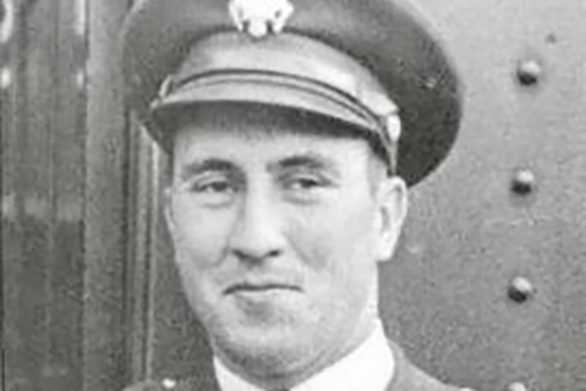 A man in a uniform and cap poses for a photo.