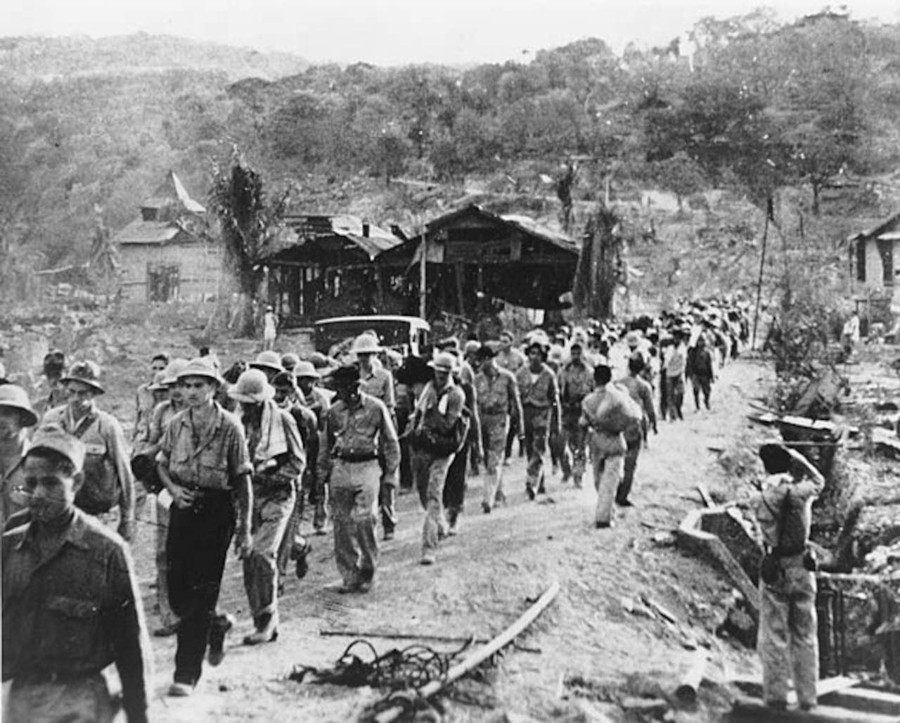 A long line of men walks along a dirty road.
