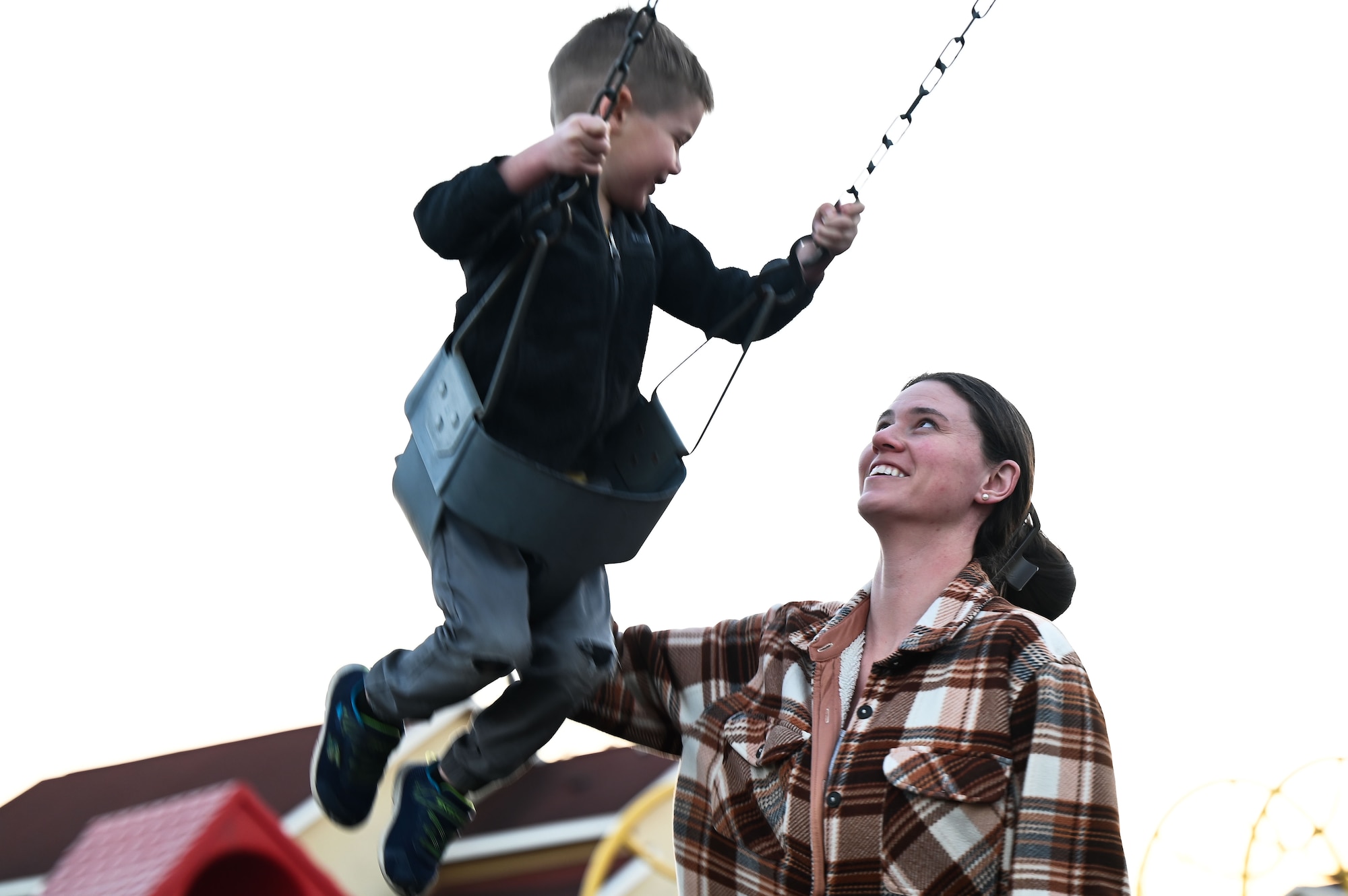U.S. Air Force Tech. Sgt. Renna Brakefield, Headquarters Air Force, Air Force Judge Advocate General's School paralegal instructor pushes her son, Harrison, on the swing at Webster Park on Maxwell Air Force Base, Alabama, Jan. 3, 2024.