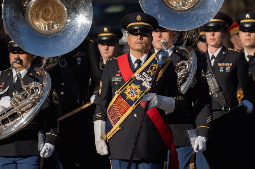 Uniformed musicians stand in formation, holding their instruments.