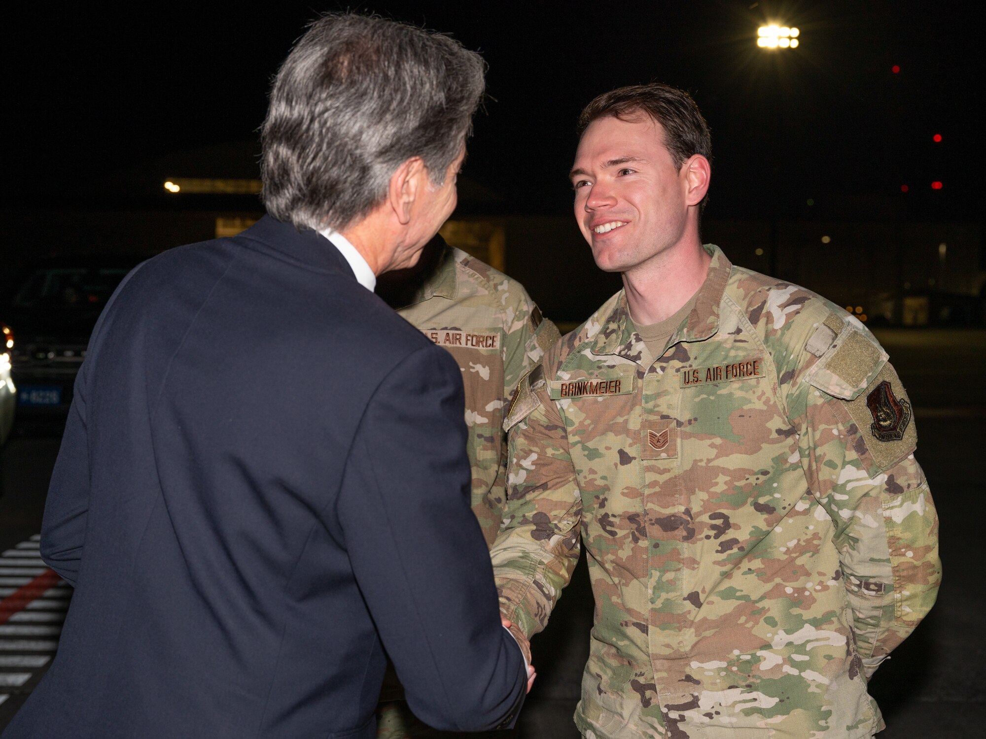 Secretary of State Antony Blinken shakes hands with U.S. Air Force Tech. Sgt. Zachary Brinkmeier, 374th Operations Support Squadron wing intelligence flight chief, at Yokota Air Base, Japan.