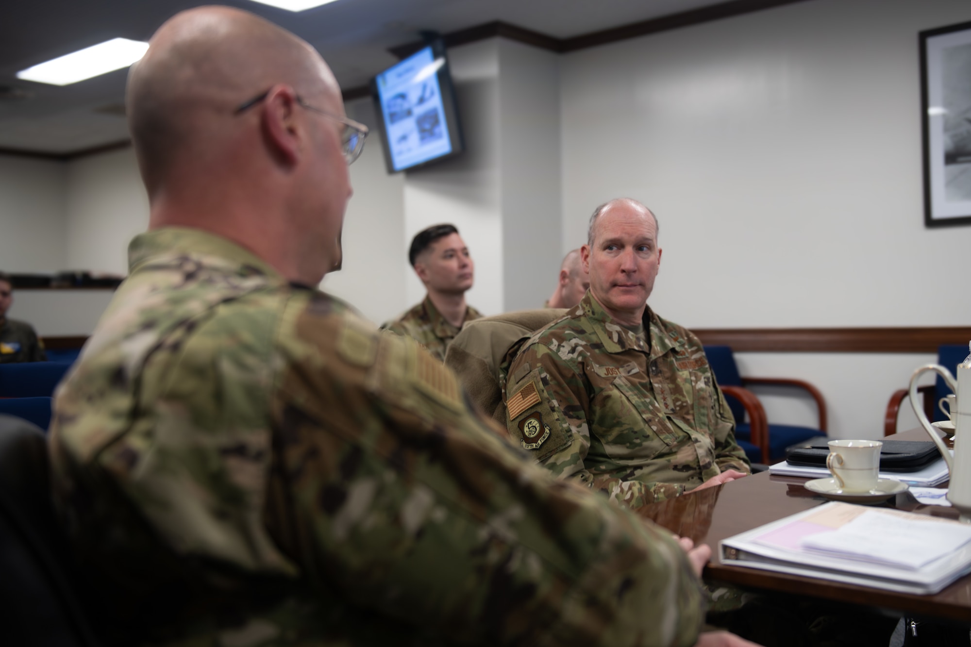 Two Air Force members sit at a table and speak to one another.