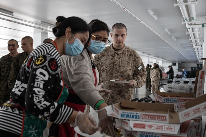 Volunteers with Marine Corps Community Services, Marine Corps Recruit Depot San Diego, pass out pizza and snacks to Marines and recruits with Special Training Company for operation happy holiday at MCRD San Diego, California, Dec. 16, 2024. MCCS hosted operation happy holiday to spread holiday cheer to recruits and Marines who will be away from family for the holiday season. (U.S. Marine Corps photo by Cpl. Sarah M. Grawcock)