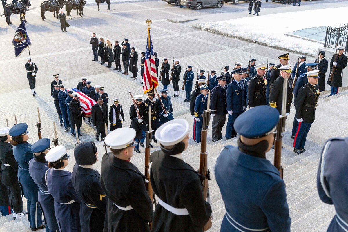Troops line the steps of the Capitol as fellow service members a carry casket covered with American flag.