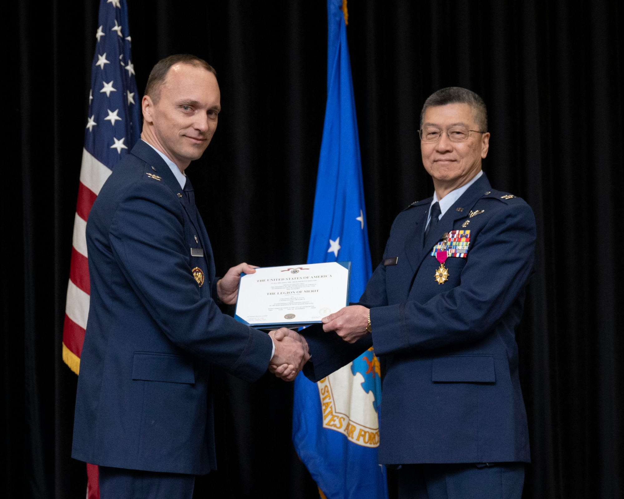 Two Air Force members holding Legion of Merit certificate