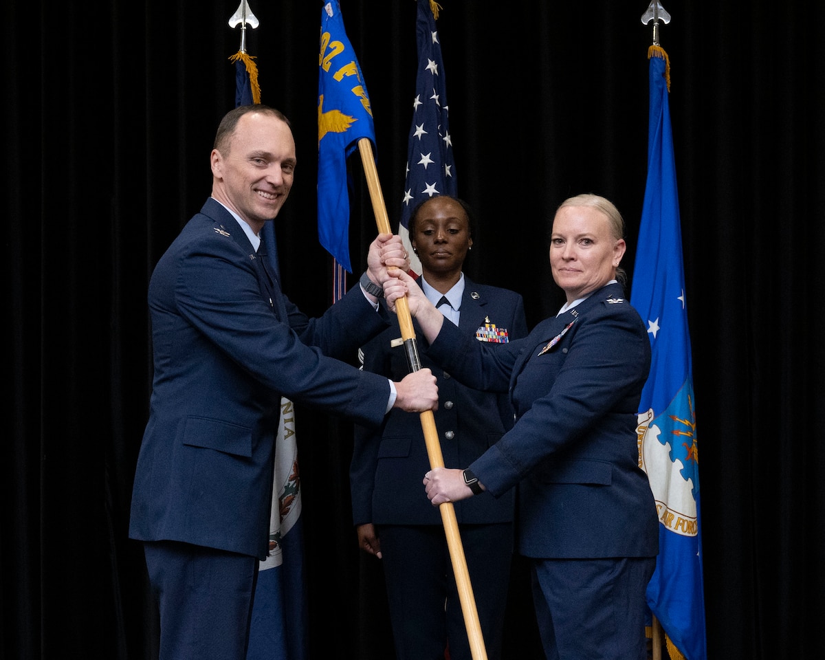 Two Air Force members holding 192nd MDG guidon with one member in the background.