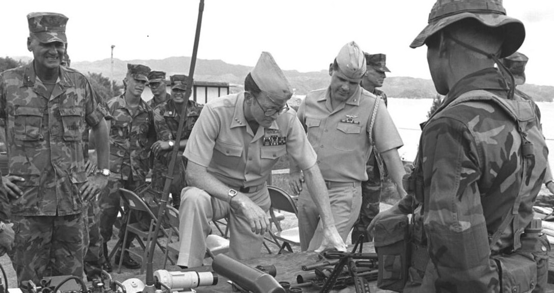 Vice Admiral James R. Hogg, commander, 7th Fleet, inspects various types of equipment used by the Marine Corps, including an M-60 machine gun, radios, and several kinds of sighting gear.