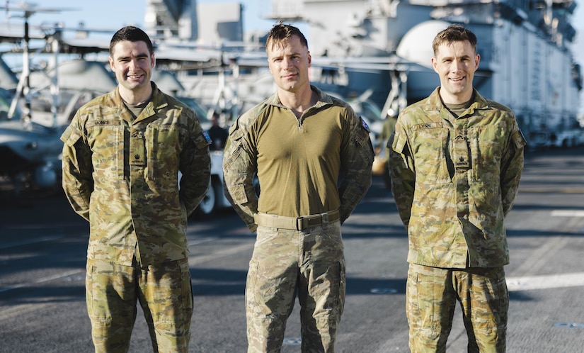 Three Australian soldiers pose for photo aboard a ship.