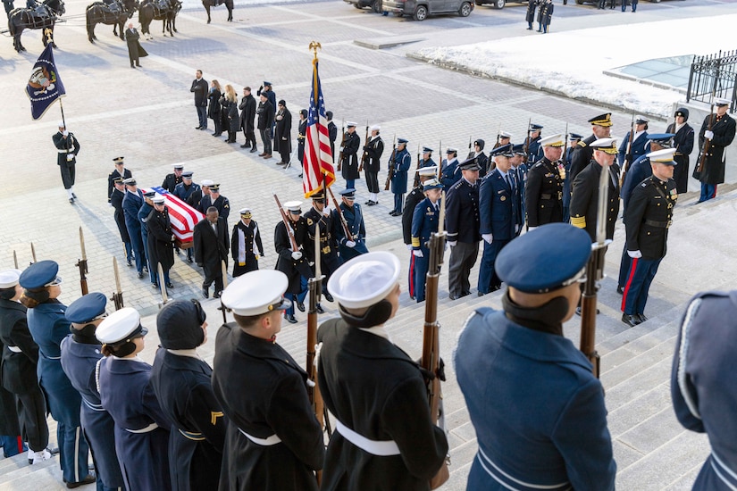 Troops line the steps of the Capitol as fellow service members a carry casket covered with American flag.