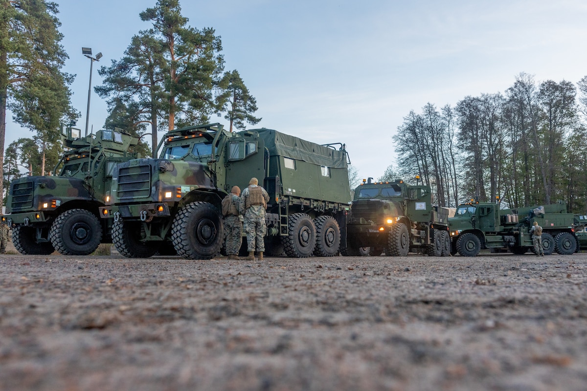Marines inspect a truck near trees.