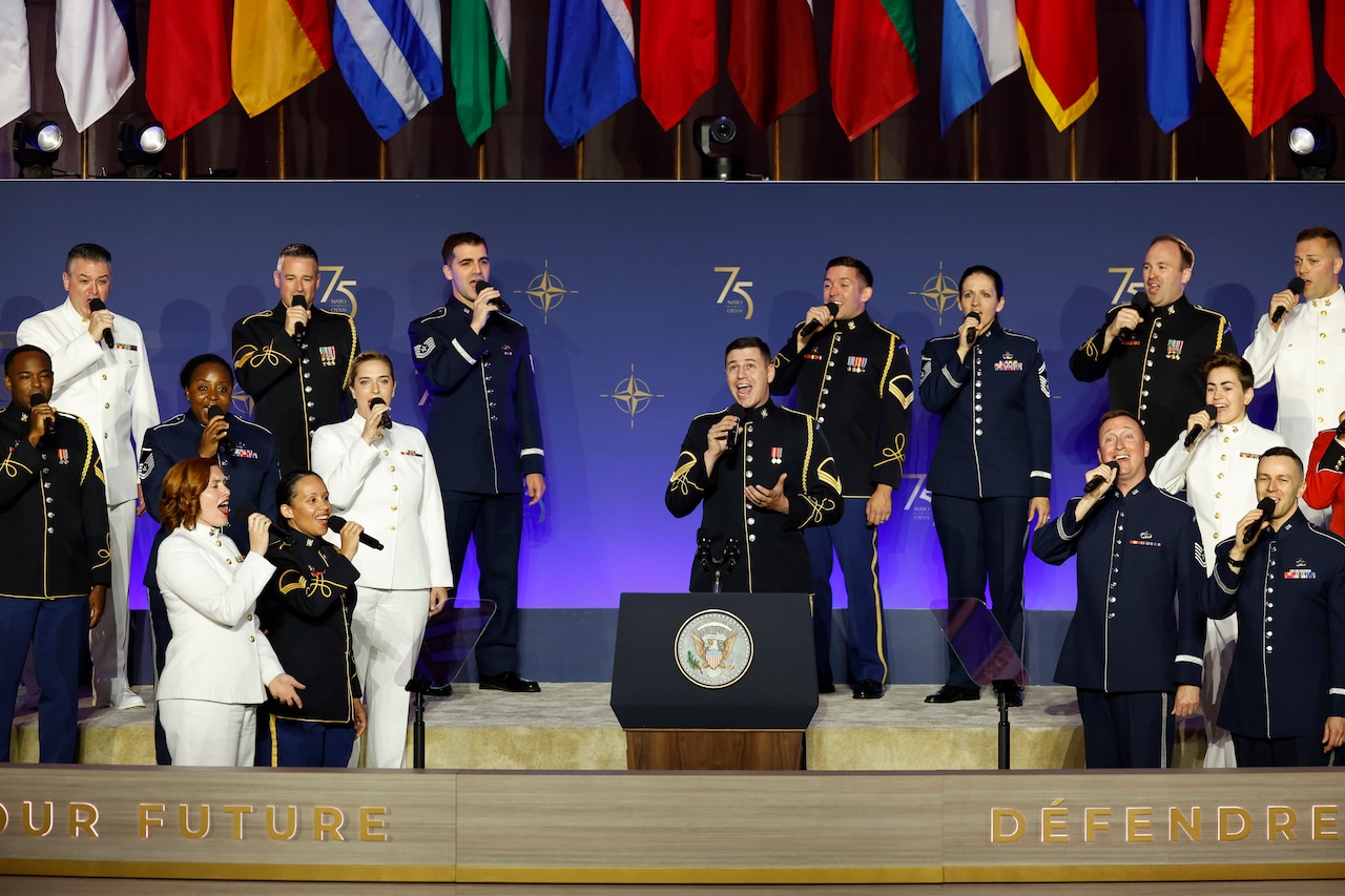 Service members from different branches sing in a chorus.