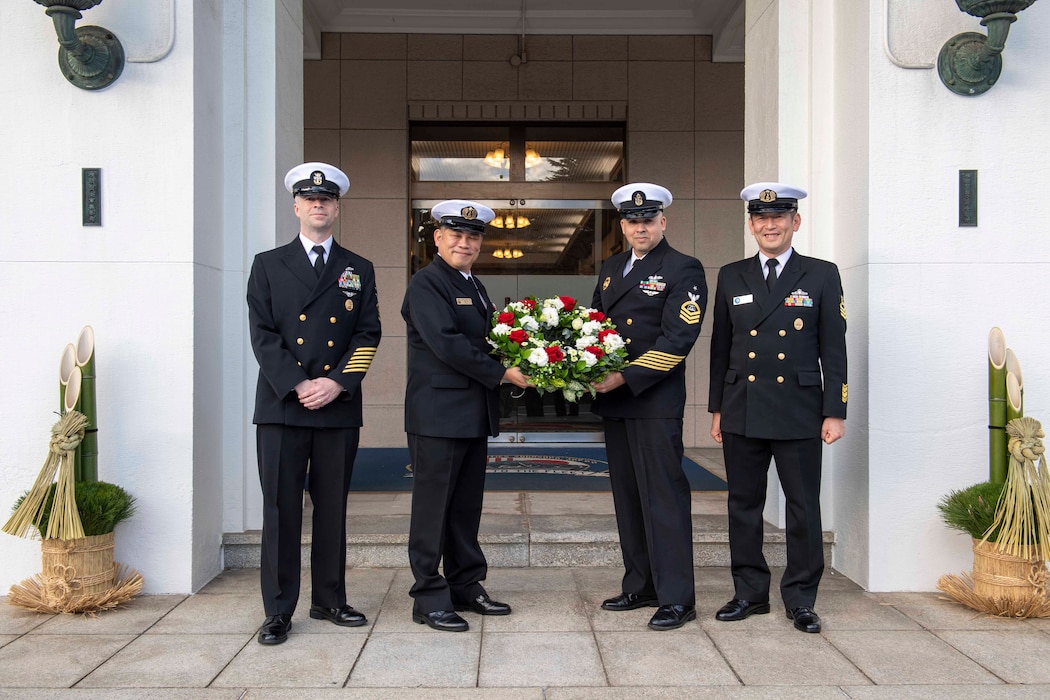 From left, Command Master Chief Dennis Hunt, from Commander, Fleet Activities Yokosuka (CFAY), Japan Maritime Self-Defense Force (JMSDF) Master Chief Petty Officer Hajime Sakai, president of the Yokosuka District Cheif Petty Officers Association, Culinary Specialist Senior Chief Steven Feriamarquez, assigned to CFAY, and JMSDF Master Chief Petty Officer Atsushi Momotake pose for a photo between two Kadomatsu ornaments during a wreath-exchange ceremony.