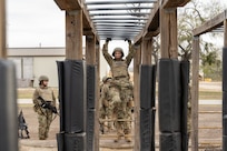 Trainee Anita Alvarez, 331st Training Squadron, hangs from the bars during the Confidence Course at PACER FORGE