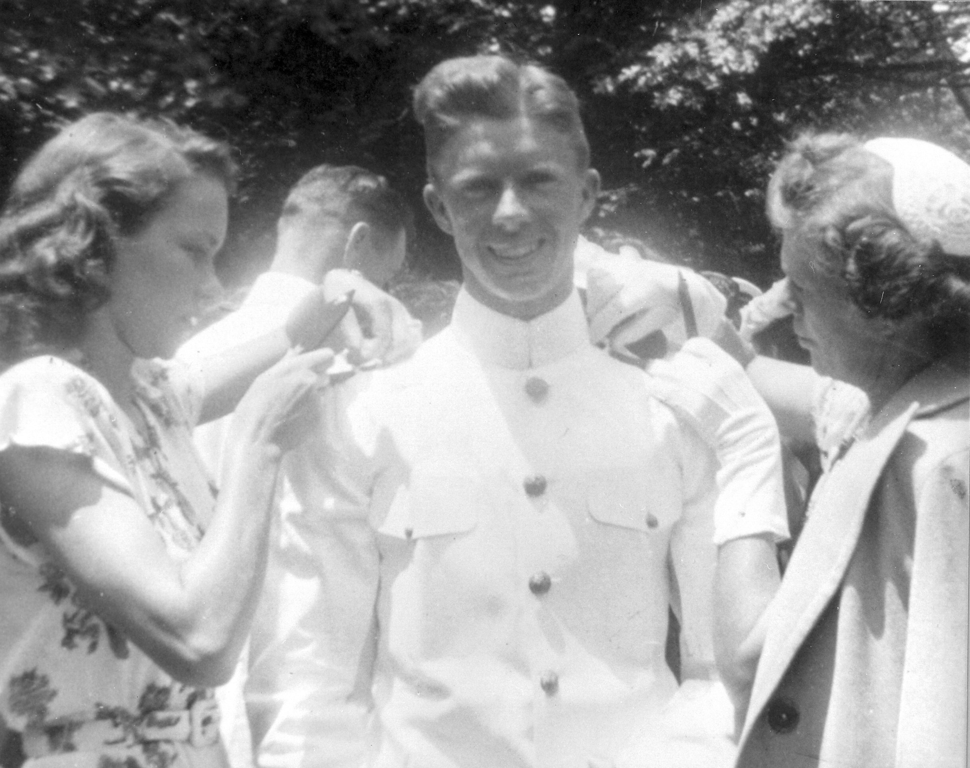 Former President Jimmy Carter becomes an ensign upon graduating from the U.S. Naval Academy, Annapolis, MD in 1946. His wife, Rosalynn Carter (Left) and mother, Bessie Cater, attaches is rank badges onto his uniform. Photo courtesy of Jimmy Carter Library and Museum.