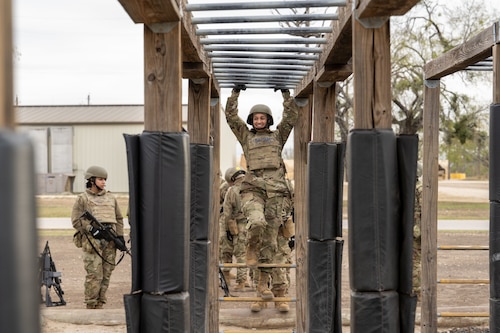 Trainee Anita Alvarez, 331st Training Squadron, hangs from the bars during the Confidence Course at PACER FORGE
