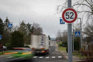 Vehicles pass by a speed limit sign.