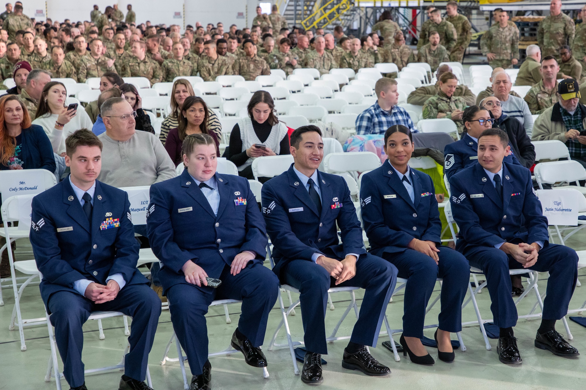 Five junior enlisted sit in a row in dress blue uniform.