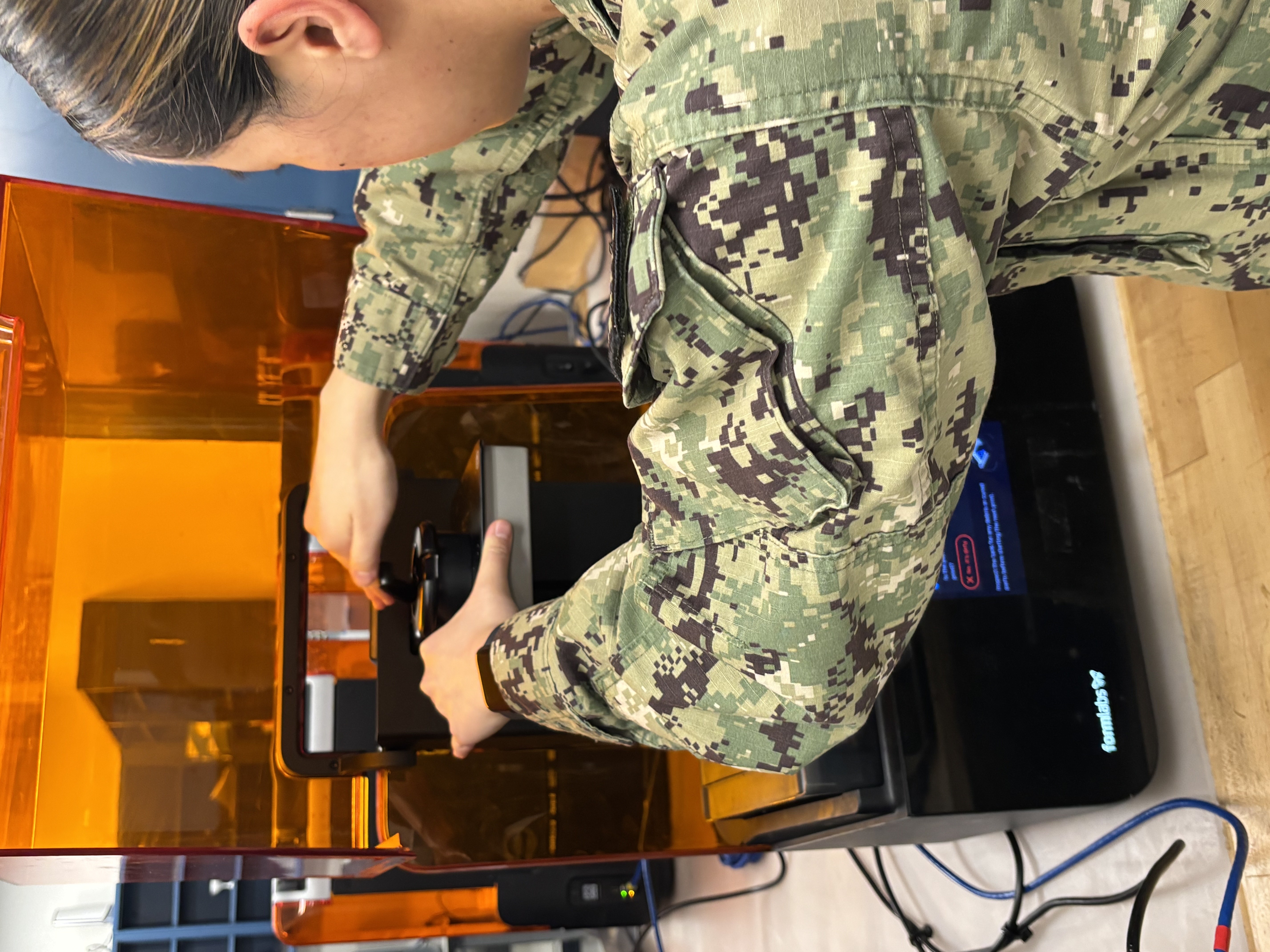 Commander, Submarine Forces is researching the usage of additive manufacturing (AM) technology to address operational needs after identifying a need for plastic dust caps, a material item essential for submarine maintenance, in collaboration with midshipmen from the U.S. Naval Academy (USNA), Submarine Squadron Two (CSS-2), Submarine Squadron Four (CSS-4), and the Portsmouth Naval Shipyard (PNSY).