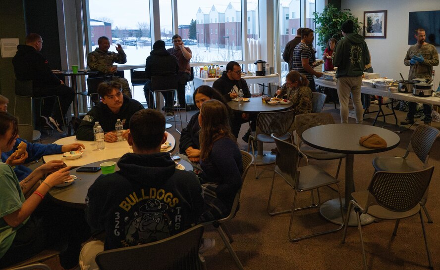 Airmen living in the dorms socialize and eat with members of the Chaplain Corps and Minot Spouses Club at Minot Air Force Base, North Dakota, Jan. 8, 2025. The dorm dinner is hosted once every month and provides Airmen with an opportunity to build community and get a free dinner. (U.S. Air Force photo by Airman 1st Class Wesley Davies)