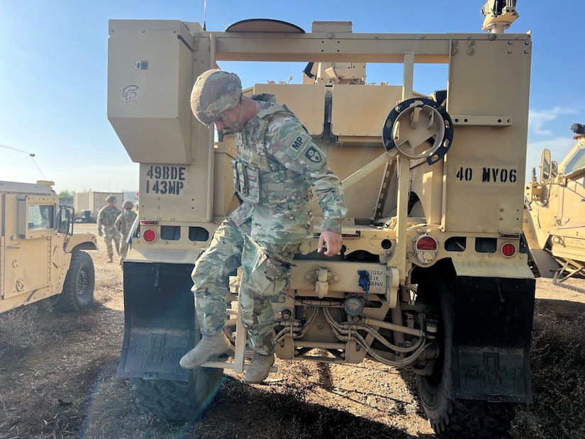 A service member is seated in the cockpit of a helicopter.