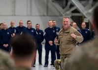 Photo of a U.S. Air Force Airman briefing service members inside a hangar.