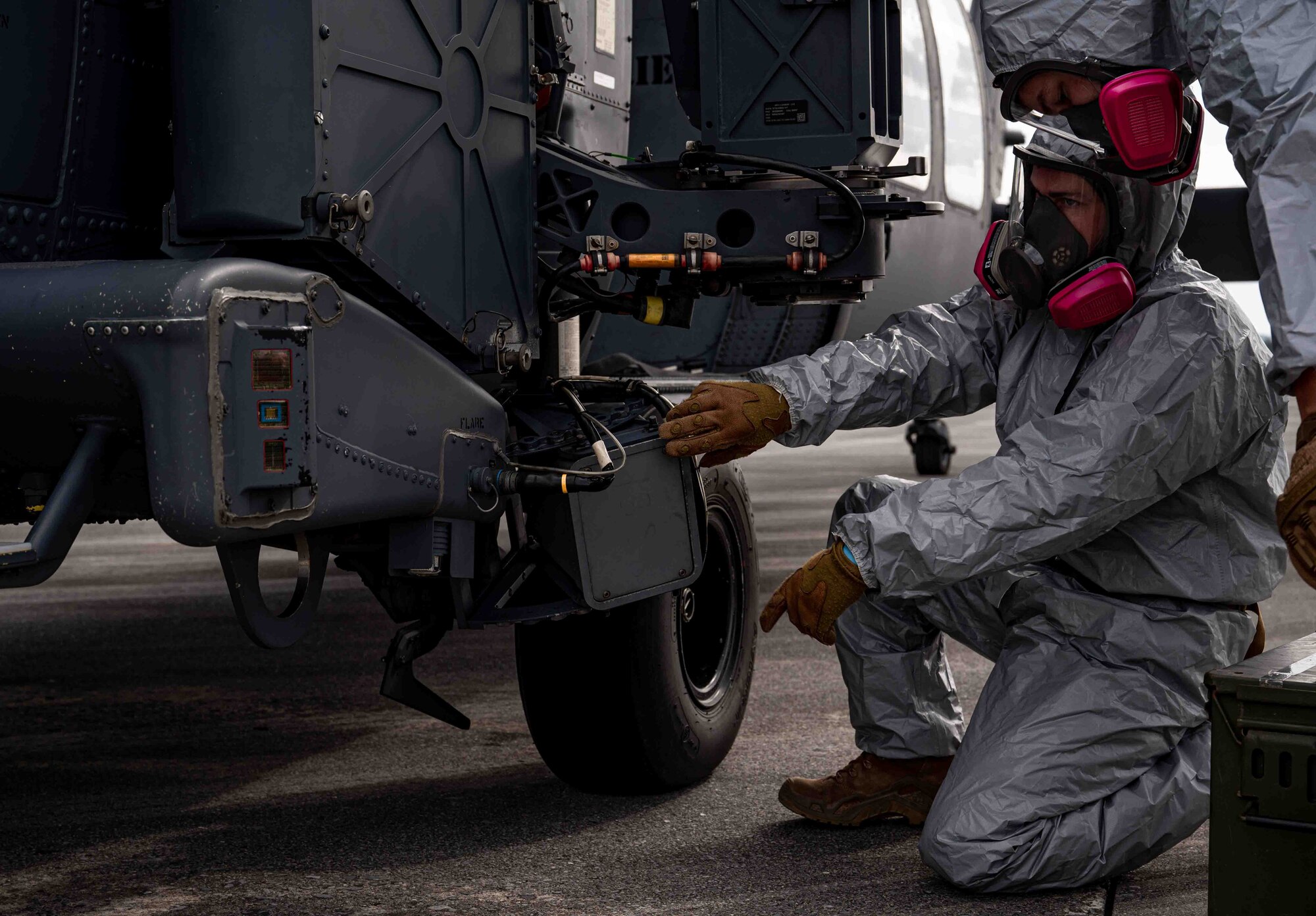 Airmen simulate removing hazardous material from a helicopter.