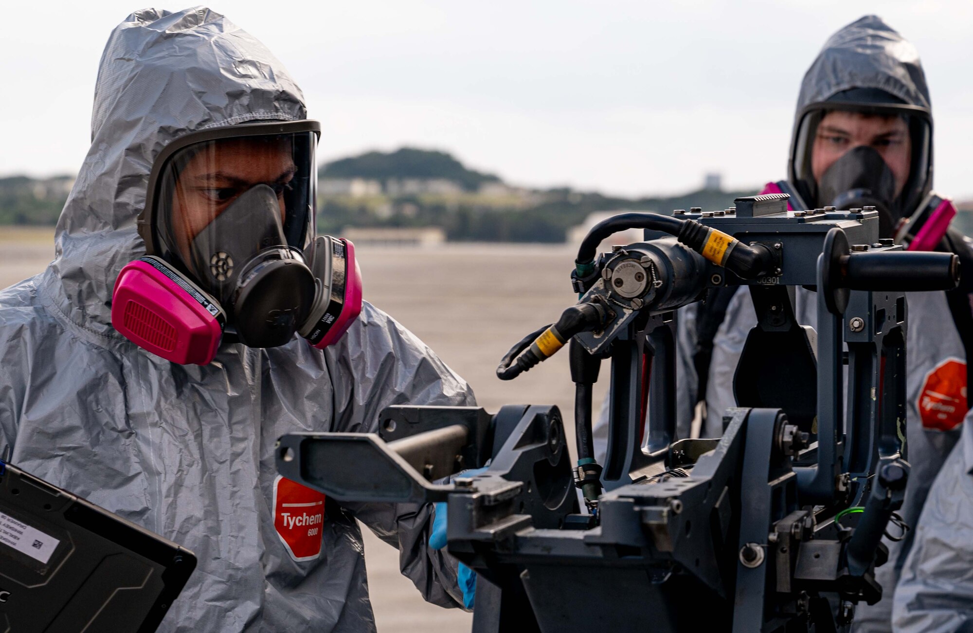 Airmen conduct safety checks on a helicopter weapons system.
