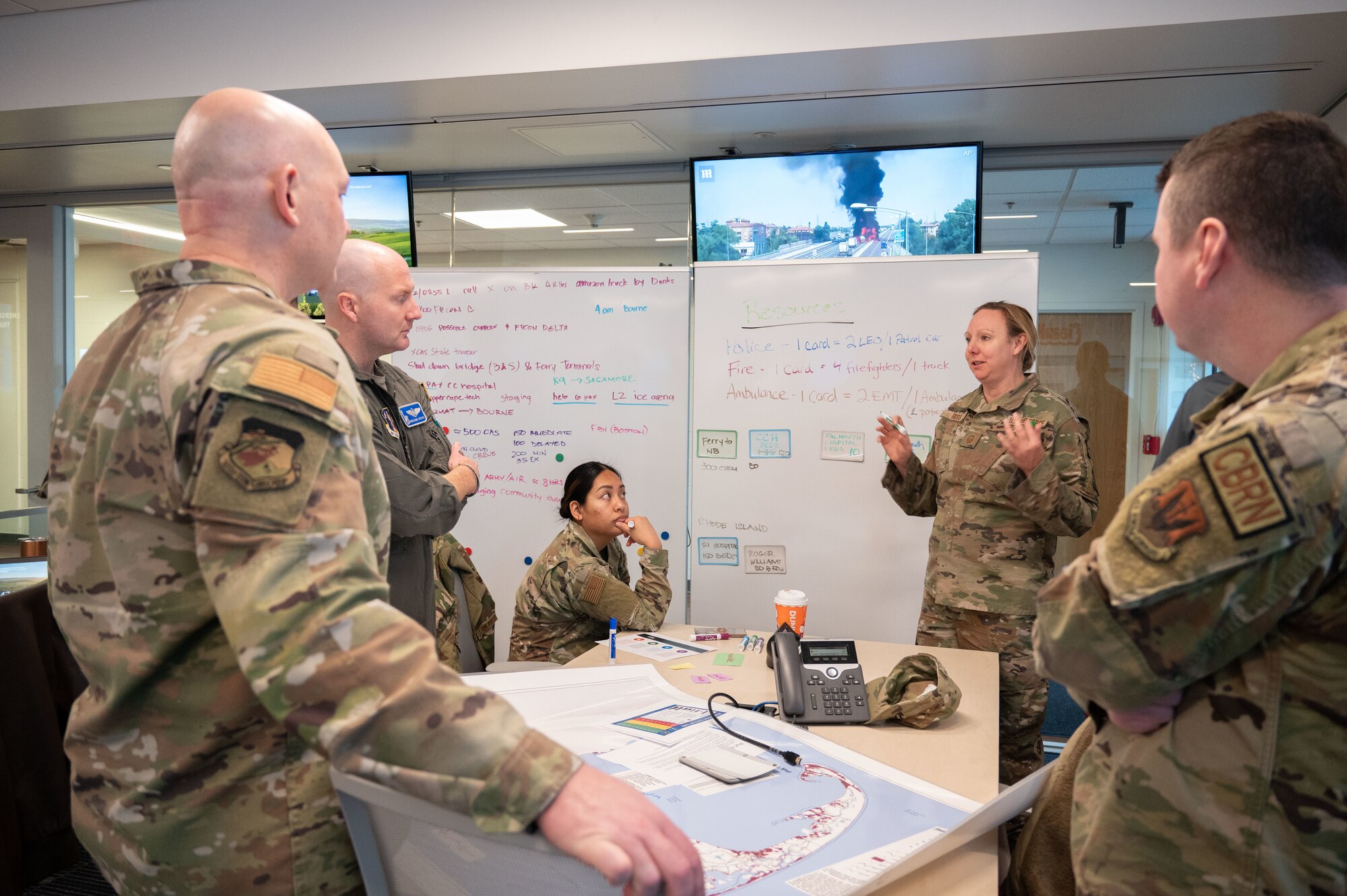 Airmen talk in front of a white board.