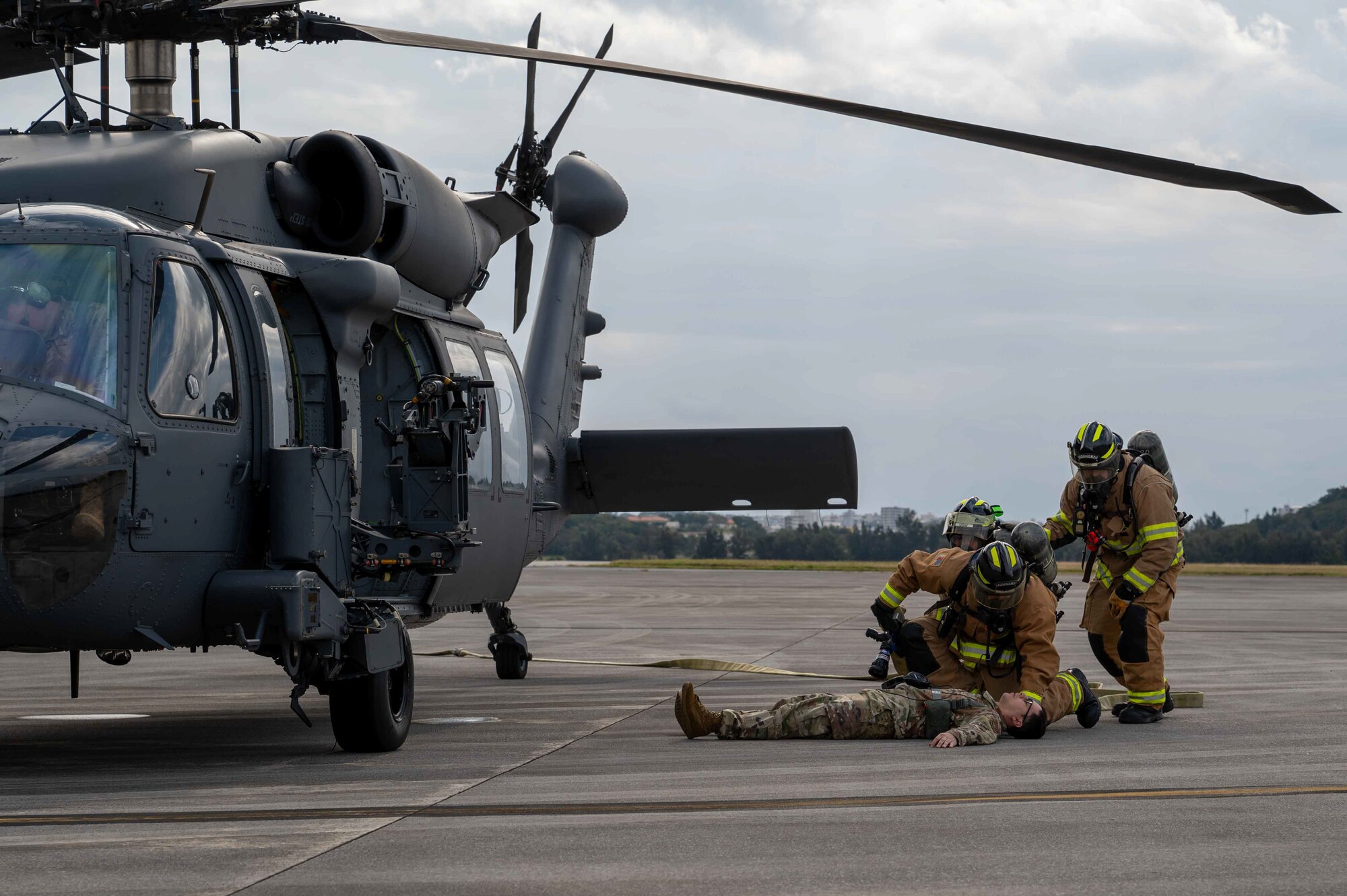 Two service member firefighters are checking on the simulated casualty that's on the ground.