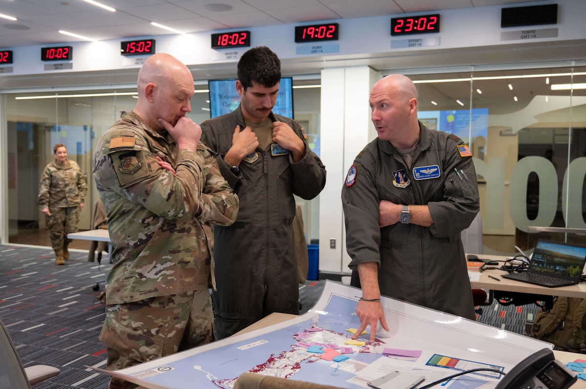 Airmen stand around a map.