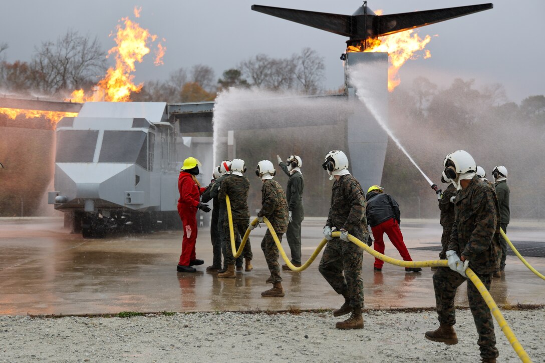 U.S. Marines with the Marine Medium Tiltrotor Squadron (VMM) 263, 2nd Marine Aircraft Wing, conduct shipboard fire fighter (SBFF) training on a mock MV-22 Osprey alongside Marine Corps Air Station (MCAS) New River Aircraft Rescue and Firefighting personnel at MCAS New River, North Carolina on Dec. 11, 2024. SBFF is designed to prepare Marines to assist Navy personnel in combatting fires on the flight deck of an amphibious vessel in an emergency situation and is a training requirement for VMM-263 prior to deployment with the 22nd Marine Expeditionary Unit. (U.S. Marine Corps photo by Cpl. Sharon Ruiz).