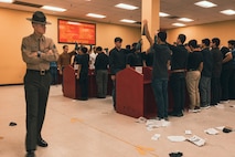 U.S. Marine Corps Drill Instructor, Sgt. Harrison Springer with Receiving Company, Support Training Battalion, briefs recruits with Delta Company, 1st Recruit Training Battalion, during a receiving event at Marine Corps Recruit Depot San Diego, California, Jan. 6, 2025. During the receiving process, recruits are taken to the United Service Organizations for accountability, checked for contraband, given haircuts, make scripted phone callls home, and issued gear required for training. Our Marines continue to serve their nation and their Corps through their lived examples of our values and by helping to identify and select potential recruits who may have what it takes to earn the title. (U.S. Marine Corps photo by Lance Cpl. Janell B. Alvarez)