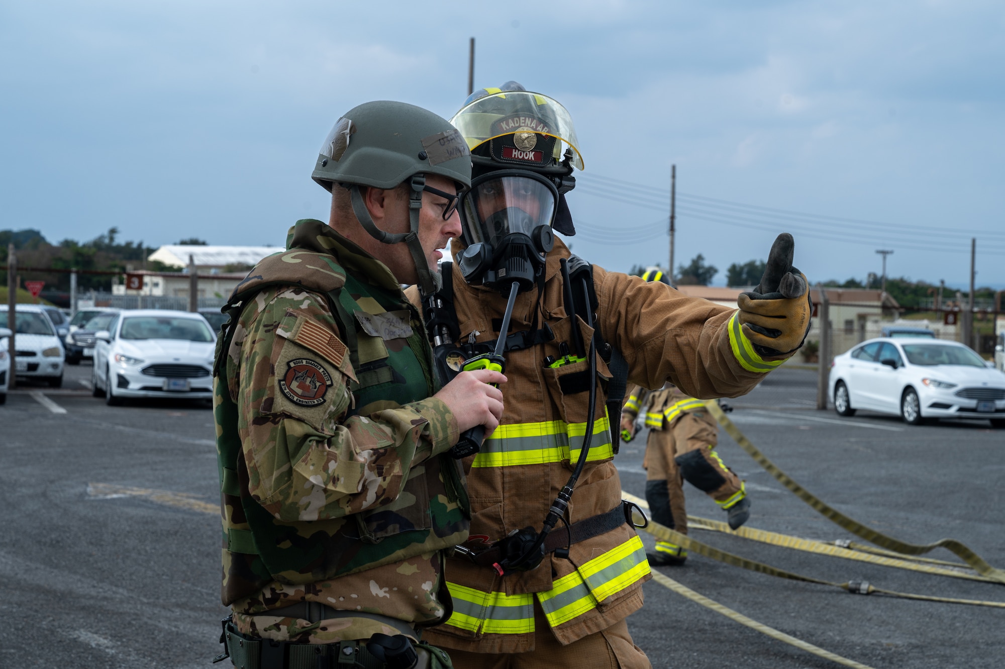 U.S. Air Force Staff Sgt. Edmond Hook firefighter assigned to the 18th Civil Engineer Squadron, right, communicates the results to a simulated structure on fire to a wing inspection team member in support of a routine readiness exercise at Kadena Air Base, Japan, Jan. 13, 2025.