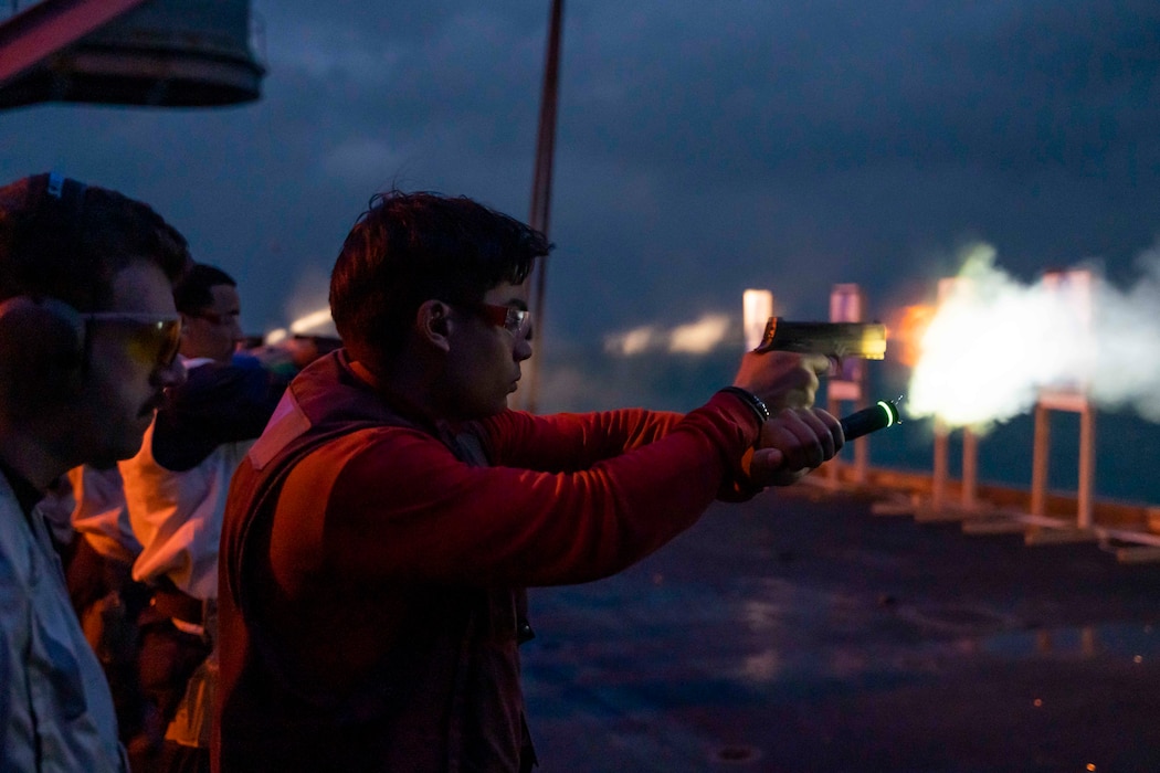 ABM3 Logan Brookshier fires an M-19 pistol during a small arms live-fire gunnery exercise aboard USS Carl Vinson (CVN 70) in the South China Sea.