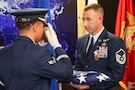 A Joint Base Langley - Eustis U.S. Air Force color guard member presents U.S. Air Force Master Sgt. Michael Powers, Joint Task Force Civil Support chief of deployed communications, with a U.S. flag in honor of his retirement, during his retirement ceremony, Fort Eustis, Va., Jan. 10, 2025. Powers retired after a 21-year career surrounded by friends and family