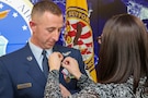 Heather Powers, right, presents her husband, U.S. Air Force Master Sgt. Michael Powers, Joint Task Force Civil Support chief of deployed communications, with the retirement pin during his retirement ceremony, Fort Eustis, Va., Jan. 10, 2025. Powers retired after a 21-year career surrounded by friends and family.