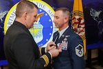 Retired U.S. Navy Lt. Cmdr. Chris Summerhill, left, presents U.S. Air Force Master Sgt. Michael Powers with the Defense Meritorious Service Medal during Powers retirement ceremony, Fort Eustis, Va, Jan. 10, 2025. Powers retired after a 21 year career surrounded by friends and family.
