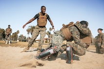 U.S. Marine Corps Martial Arts Instructor Trainer, Sgt. David Hamptonfur with Support Battalion, Recruit Training Regiment, Marine Corps Recruit Depot San Diego, observes Marines participate in a culminating event during a Marine Corps Martial Arts Instructor Course at MCRD San Diego, California, Dec. 18, 2024. After three weeks of training, MAI Course Class 19-24 conducted a five-hour culminating event that challenged students to show expertise in ground fighting, weapons-free sparring, and bayonet and knife techniques. (U.S. Marine Corps photo by Cpl. Sarah M. Grawcock)