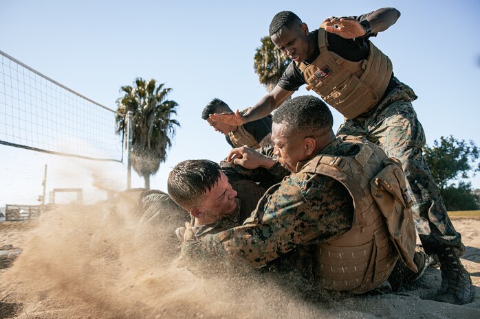 U.S. Marine Corps Martial Arts Instructor Trainer, Sgt. David Hamptonfur with Support Battalion, Recruit Training Regiment, Marine Corps Recruit Depot San Diego, observes Marines participate in a culminating event during a Marine Corps Martial Arts Instructor Course at MCRD San Diego, California, Dec. 18, 2024. After three weeks of training, MAI Course Class 19-24 conducted a five-hour culminating event that challenged students to show expertise in ground fighting, weapons-free sparring, and bayonet and knife techniques. (U.S. Marine Corps photo by Cpl. Sarah M. Grawcock)