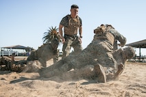 U.S. Marine Corps Martial Arts Instructor Trainer, Staff Sgt. Patrick Chok with Support Battalion, Marine Corps Recruit Depot San Diego, observes Marines participating in a culminating event during a Marine Corps Martial Arts Instructor Course at MCRD San Diego, California, Dec. 18, 2024. After three weeks of training, MAI Course Class 19-24 conducted a five-hour culminating event that challenged students to show expertise in ground fighting, weapons-free sparring, and bayonet and knife techniques. (U.S. Marine Corps photo by Cpl. Sarah M. Grawcock)