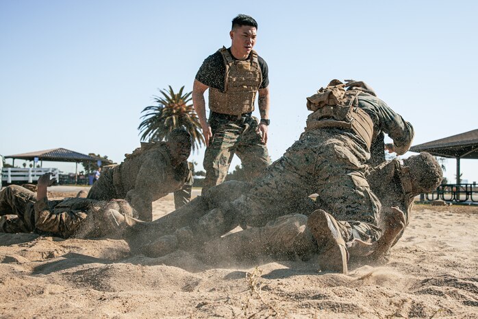U.S. Marine Corps Martial Arts Instructor Trainer, Staff Sgt. Patrick Chok with Support Battalion, Marine Corps Recruit Depot San Diego, observes Marines participating in a culminating event during a Marine Corps Martial Arts Instructor Course at MCRD San Diego, California, Dec. 18, 2024. After three weeks of training, MAI Course Class 19-24 conducted a five-hour culminating event that challenged students to show expertise in ground fighting, weapons-free sparring, and bayonet and knife techniques. (U.S. Marine Corps photo by Cpl. Sarah M. Grawcock)