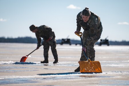 U.S. Airmen assigned to the 816th Security Forces Squadron remove ice and snow from the flight line at Joint Base Andrews, Md., Jan. 7, 2025. Members across the installation worked together to clear the flight line prior to the arrival ceremony for the State Funeral of former President Jimmy Carter. (U.S. Air Force photo by Staff Sgt. Alex Broome) (This photo has been altered for security purposes by removing identification badges)